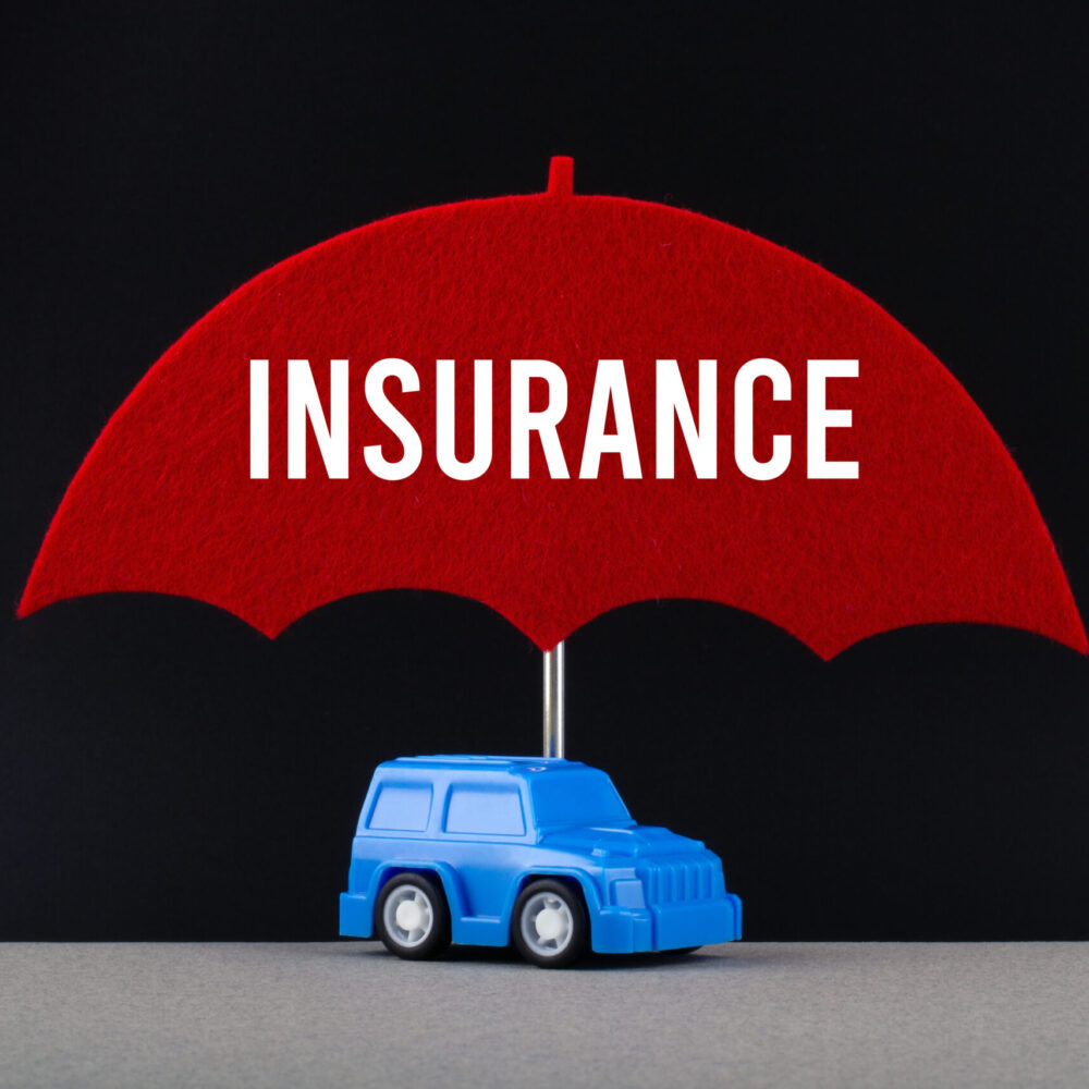 Concept of car insurance. Blue car under red umbrella with text Insurance. Concept of car insurance. Blue car under red umbrella with text Insurance