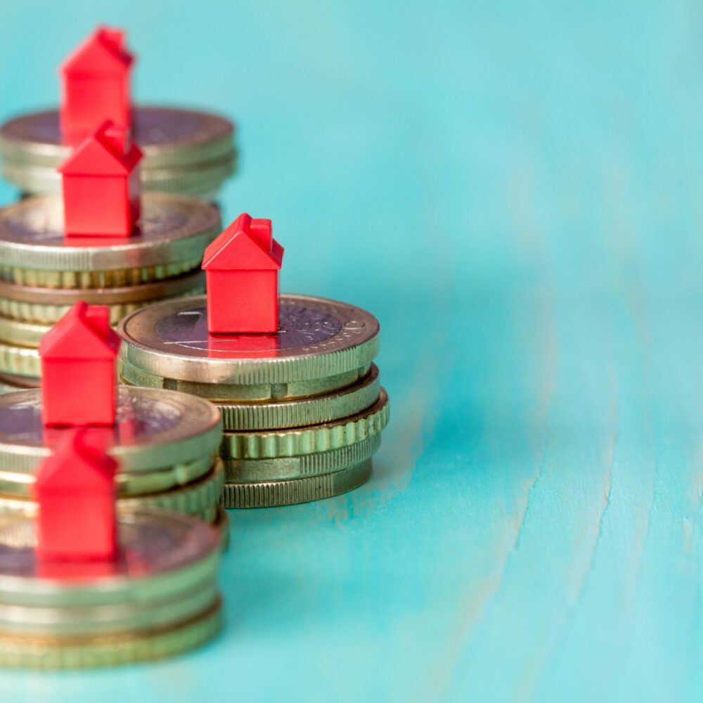 Coins in a row with mini houses Real estate mortgage concept with small house models on coins row